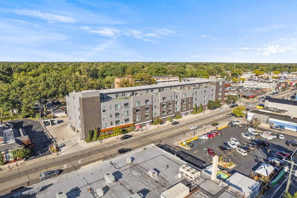 an aerial view of a large apartment building with a parking lot and trees in the background