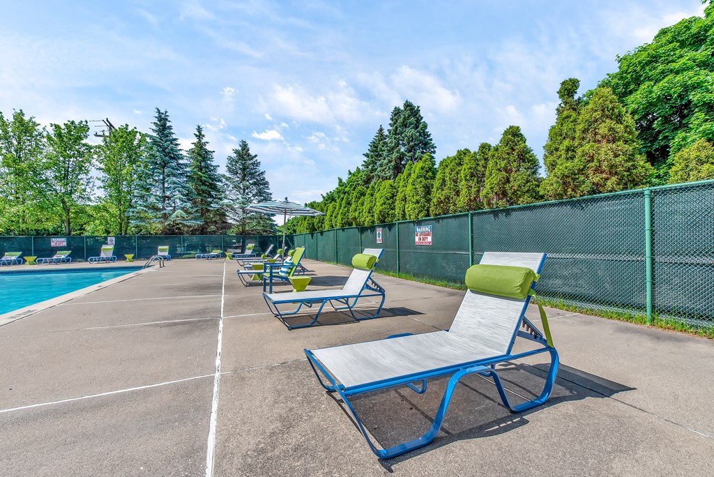 a group of lounge chairs on a tennis court next to a pool