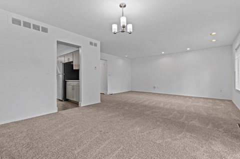the living room and dining room of a new home with white walls and carpet