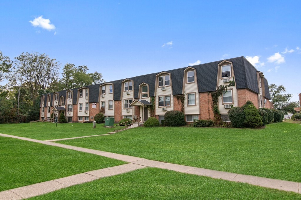 an apartment building with green grass and a sidewalk