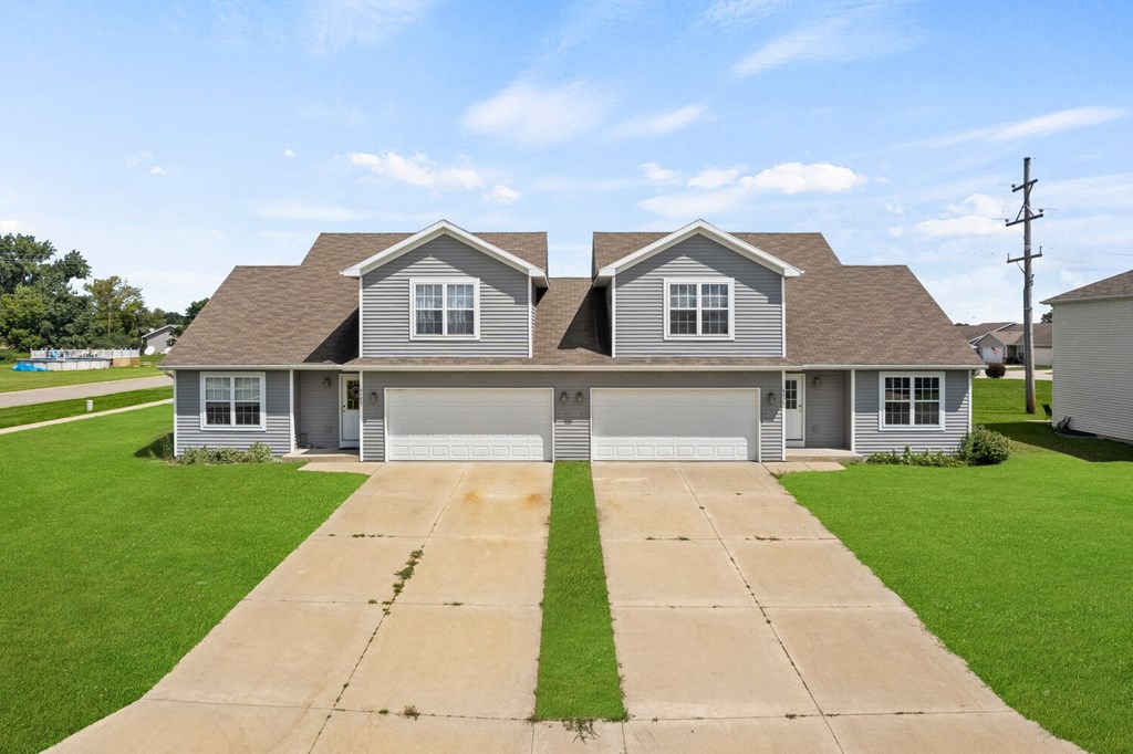 a gray house with a garage and a lawn