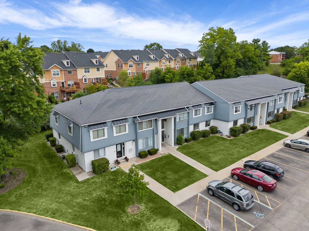 a group of blue houses with cars parked in a parking lot