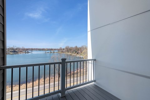 A balcony overlooks a body of water with boats and trees in the distance.