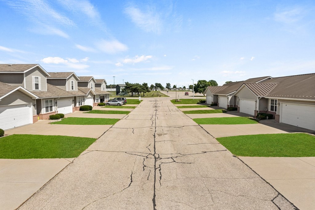 a street with rows of houses on either side of a cracked road