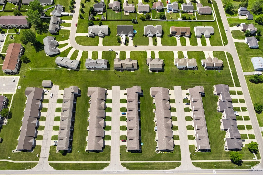 an aerial view of a neighborhood with cars parked on the grass