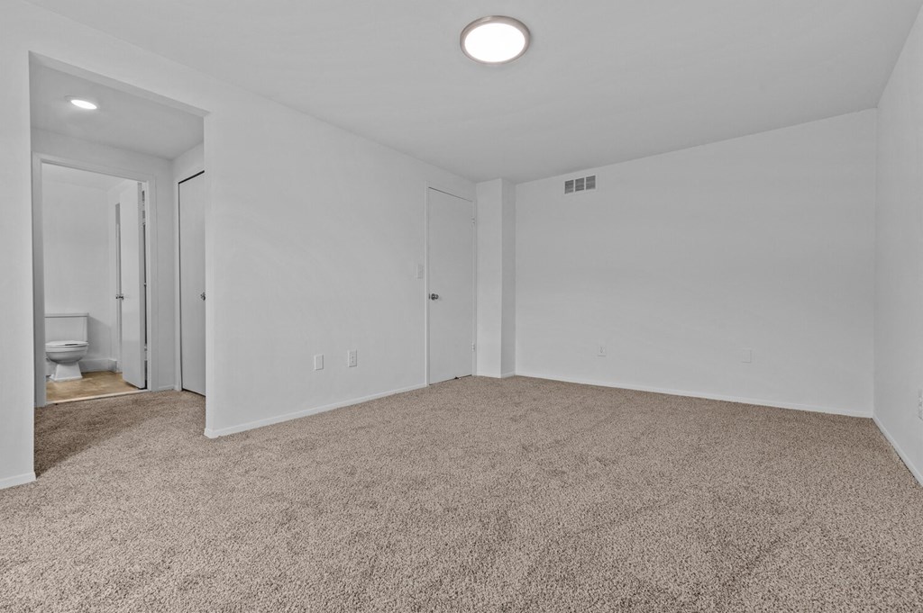 an empty living room with carpet and a door to a bathroom at Edge At Farmington Hills - Farmington Hills, MI, Michigan, 48334