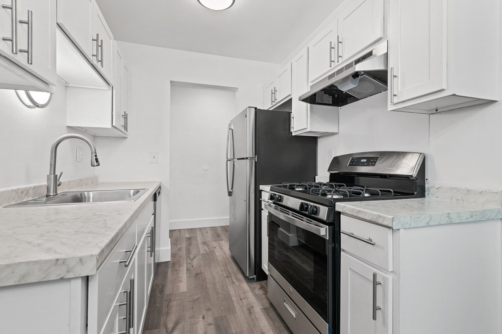 an all white kitchen with stainless steel appliances and marble counter tops