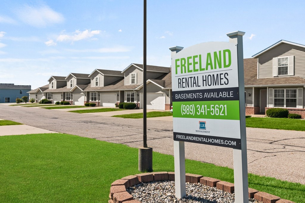 a freedom rental homes real estate sign in front of houses
