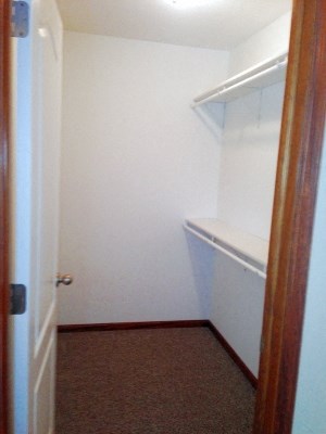 a small room with a white closet and a brown carpet
