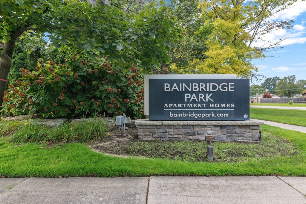 a sign in a grassy area with trees in the background