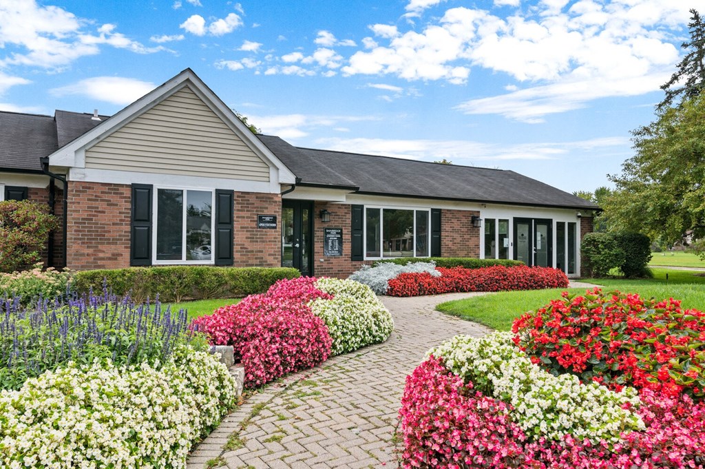 a brick house with a brick walkway and colorful flowers in front of it