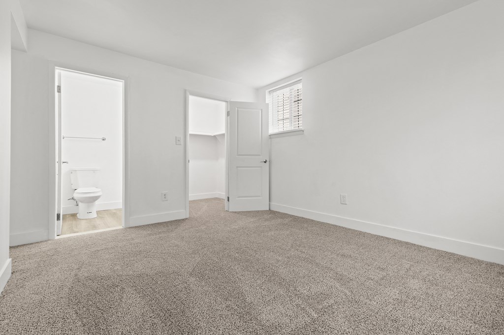 an empty living room with carpet and a white bathroom