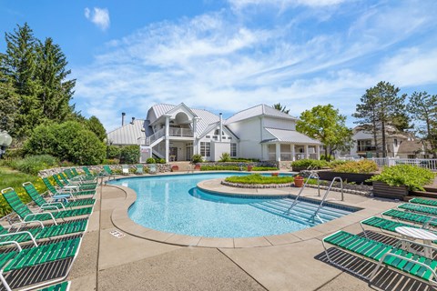 A large swimming pool with lounge chairs and a building in the background.