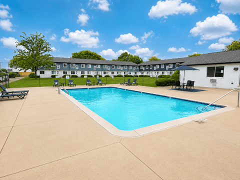A large swimming pool in front of a building with a white exterior.
