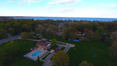 an aerial view of a pool and a house in front of a lake