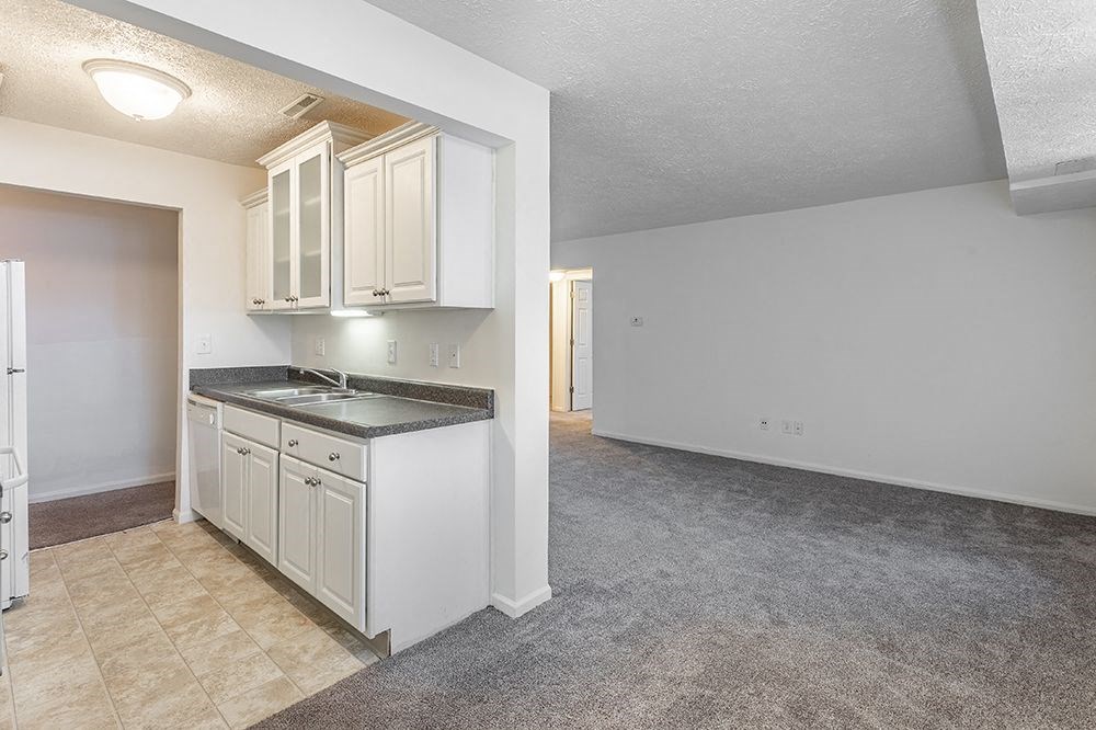 an empty kitchen with white cabinets and a sink