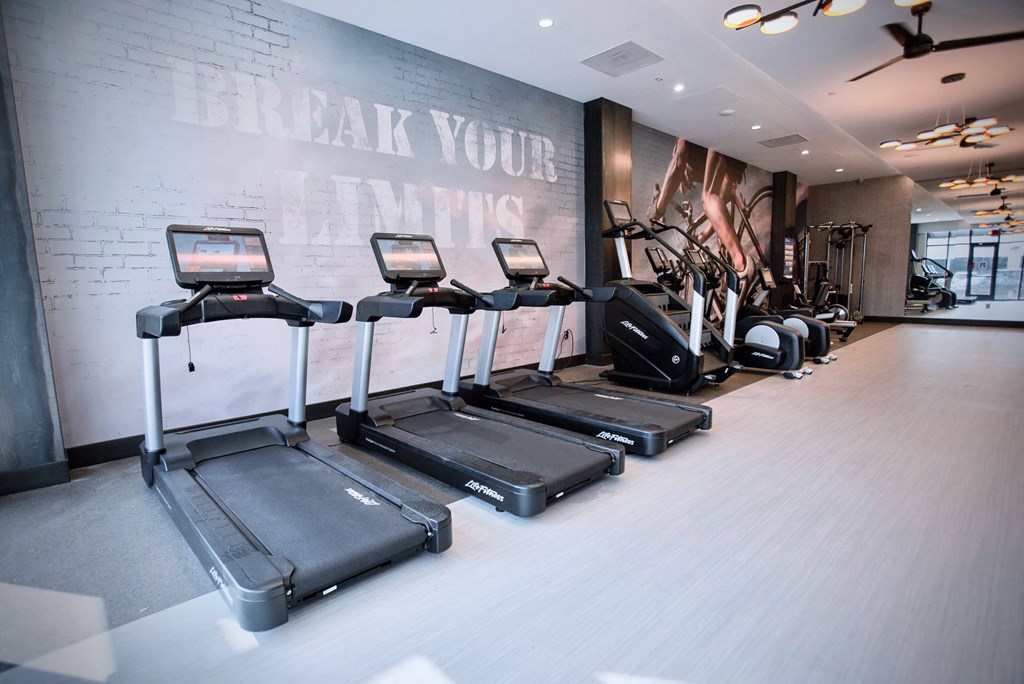 a gym with cardio equipment and a wall that says break your limitations