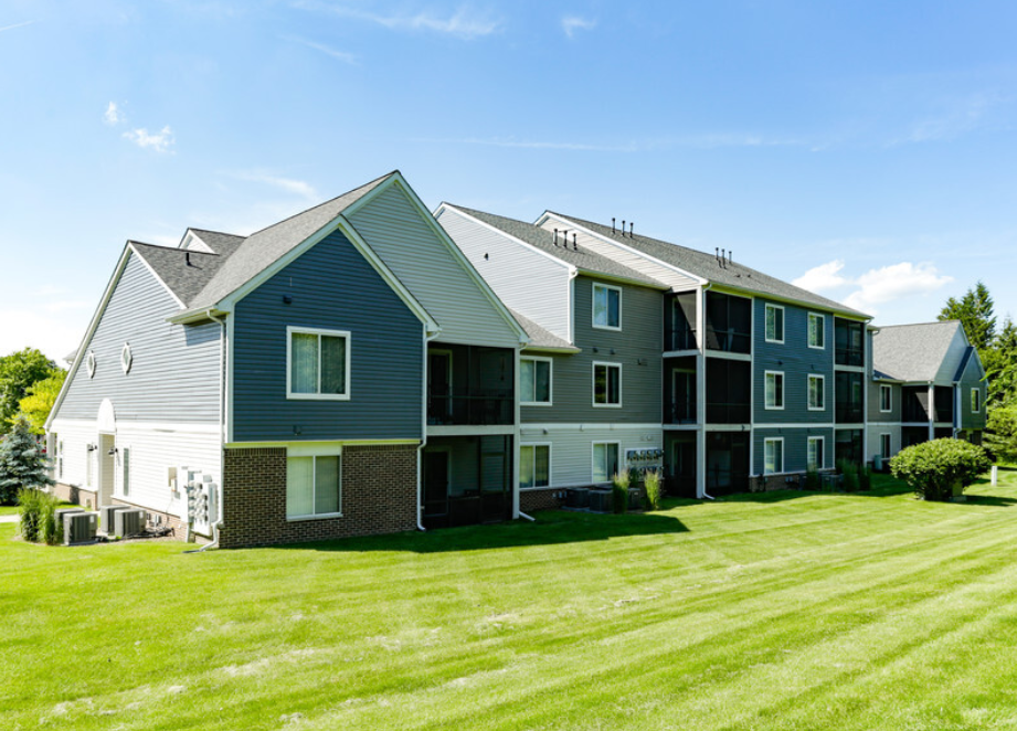 a large apartment building with a green lawn