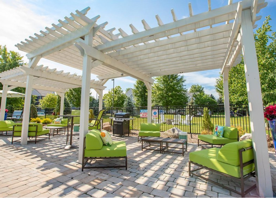 a patio with green couches and chairs under a white canopy