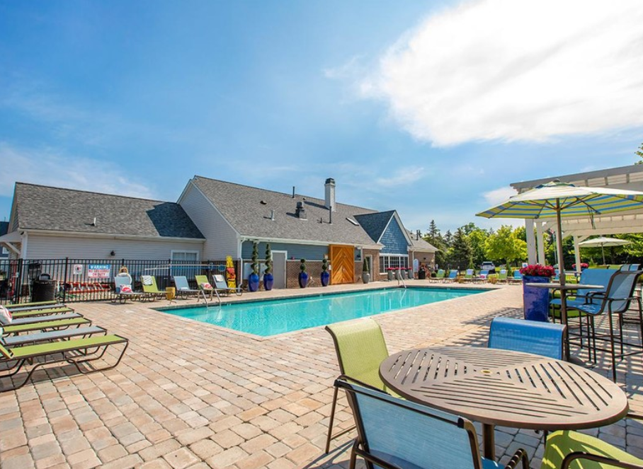 a swimming pool with chairs and tables next to a house