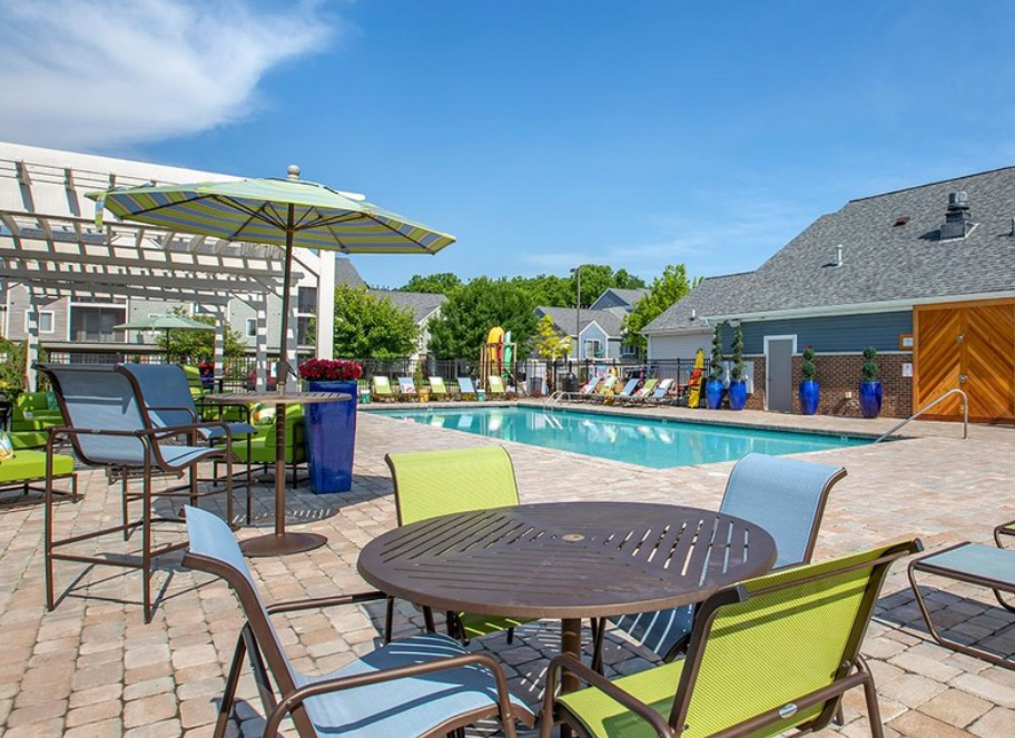 a swimming pool with a patio with tables and chairs