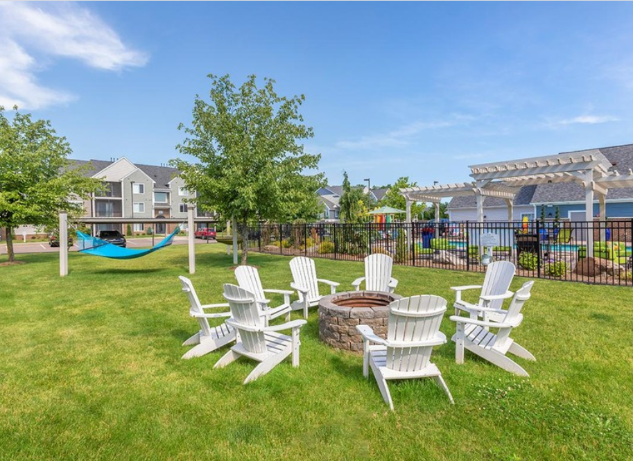 a group of chairs sitting around a fire pit in the grass