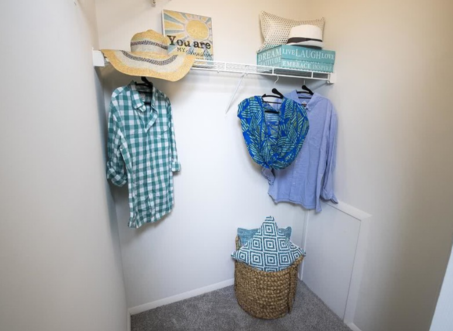 a closet with clothes and a hat on the wall