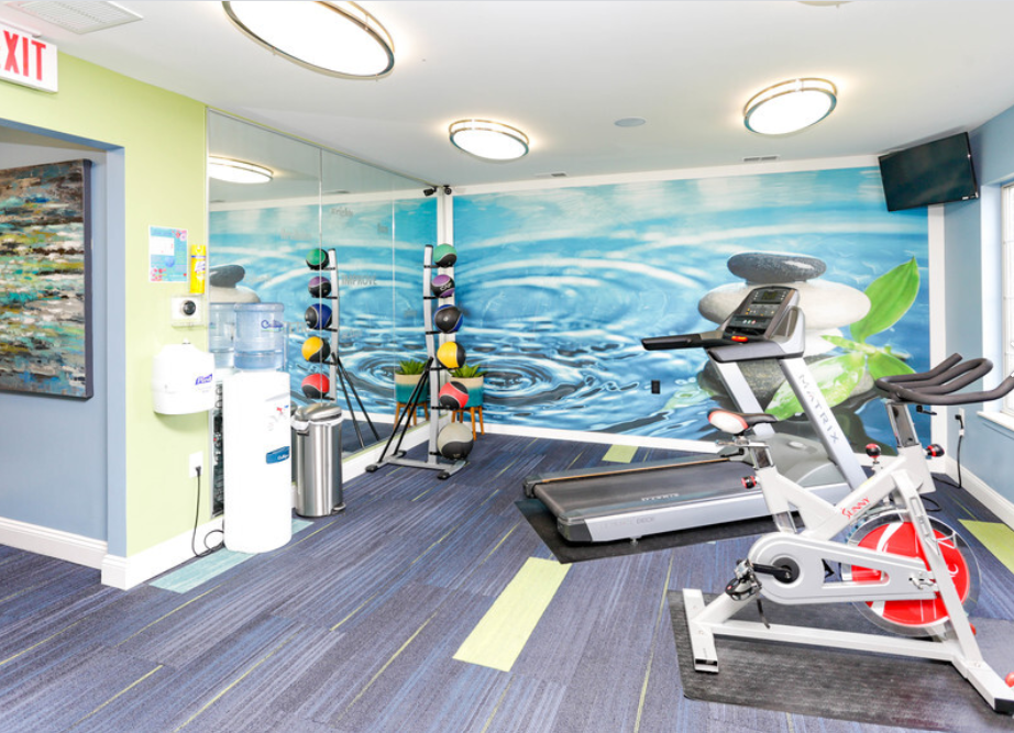 a gym with exercise equipment and a mural on the wall