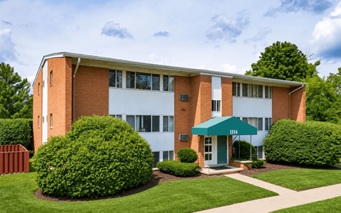 A building with a green awning and bushes in front.