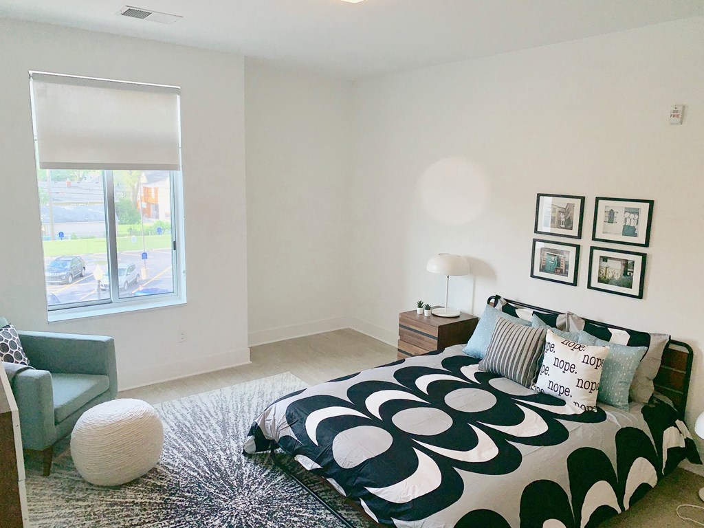 a bedroom with a bed and a chair and a window