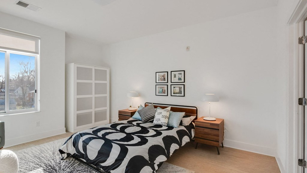 a bedroom with white walls and a bed with a black and white comforter