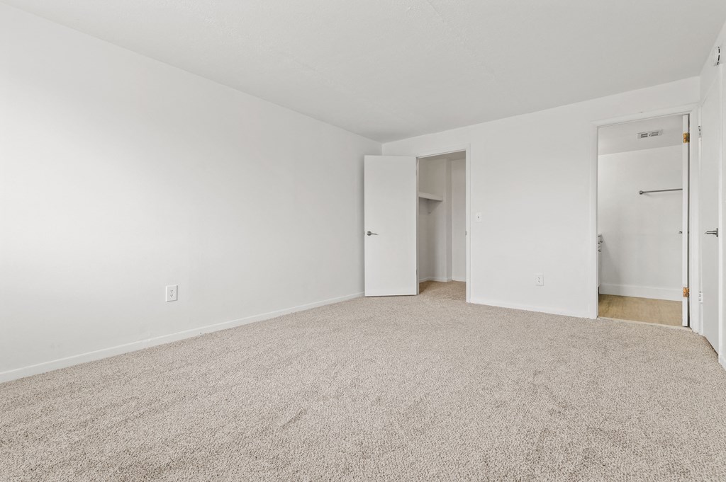 an empty living room with white walls and carpet