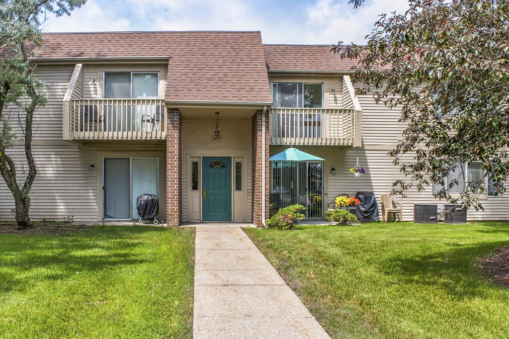 a white house with a blue door and a lawn