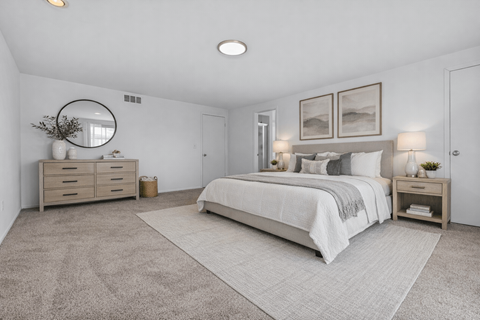 A bedroom with a large bed, a dresser, and a mirror.