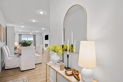 A modern living room with a white sofa set, a coffee table with a lamp, and a vase of yellow flowers.