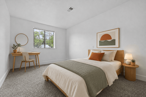 A bedroom with a large bed and a desk with a chair.