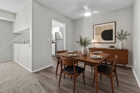 A dining room with a table set for two and a painting on the wall.