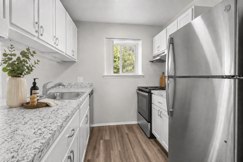 A kitchen with white cabinets and a marble countertop.