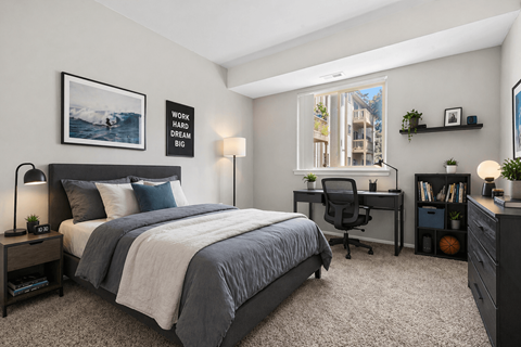 A bedroom with a bed, desk, and chair.