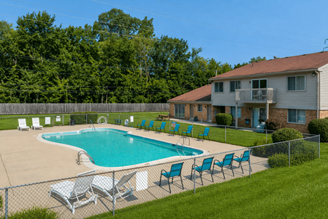 A pool with chairs around it and a house in the background.