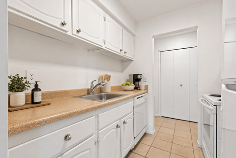 A kitchen with white cabinets and a beige countertop.