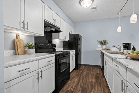A kitchen with black appliances and white cabinets.