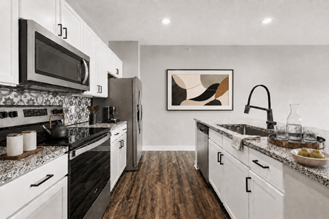 A modern kitchen with white cabinets and a black stove top.