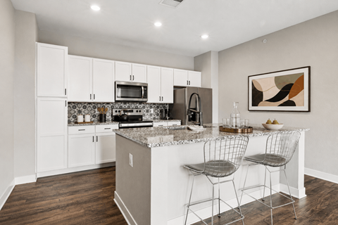 A kitchen with white cabinets and a granite countertop.