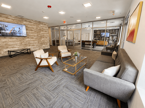 A modern living room with a grey carpet and a stone wall.