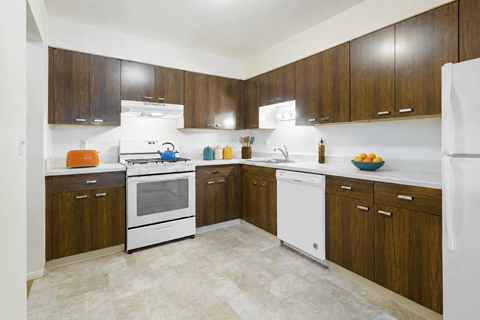 A kitchen with white appliances and wooden cabinets.