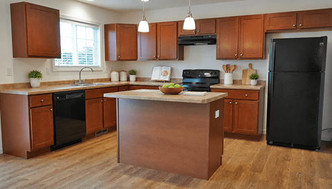 A kitchen with wooden cabinets and a black refrigerator.
