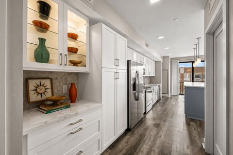 A kitchen with white cabinets and a wooden floor.