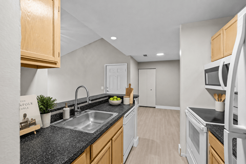 A kitchen with a black granite countertop and wooden cabinets.