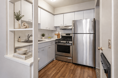 A modern kitchen with a stainless steel refrigerator and white cabinets.